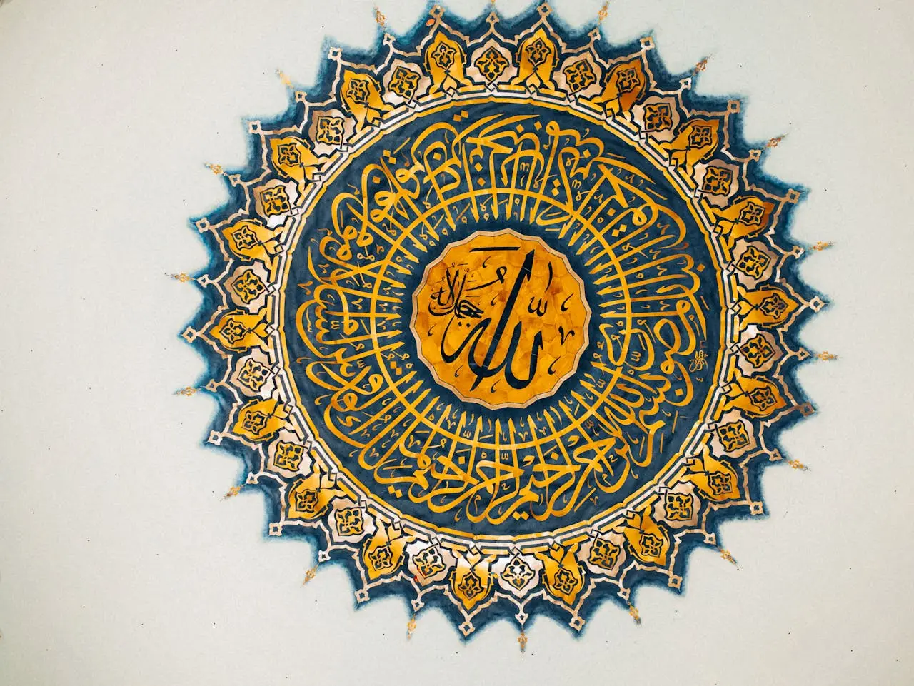 our-experience Elegant Arabic calligraphy in blue and gold adorns a mosque ceiling, showcasing Islamic art.