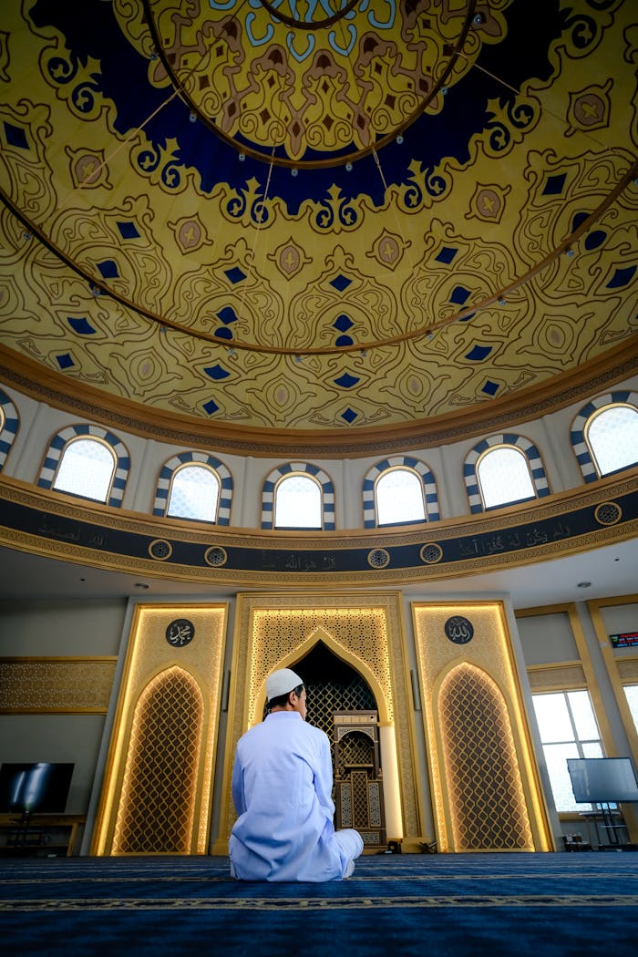 services-03 A man peacefully praying inside a beautifully designed mosque, highlighting Islamic architecture.