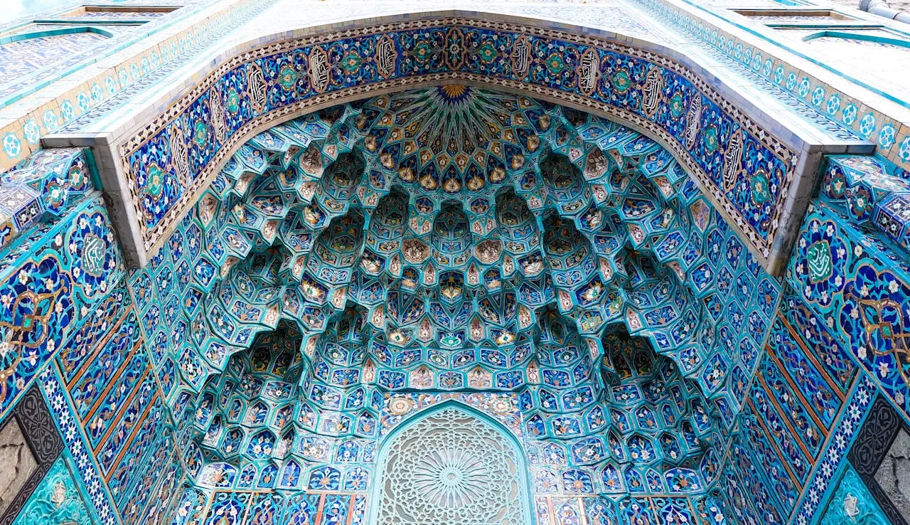 services-04 A close-up view of an ornate Islamic dome with vibrant blue mosaic patterns and geometric design.
